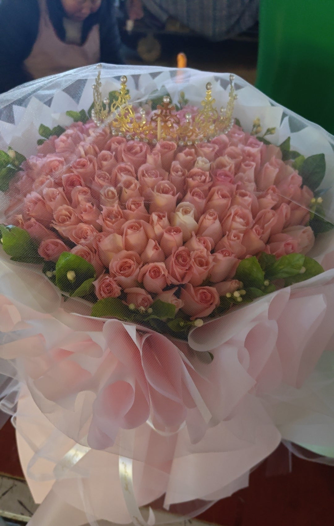 Bouquet of pink flowers with candles on top, placed on a white surface.