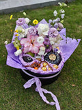 Bouquet of flowers with fruits wrapped in purple paper on a grassy background