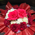 Bouquet of red and white flowers with red tissue paper on a dark surface